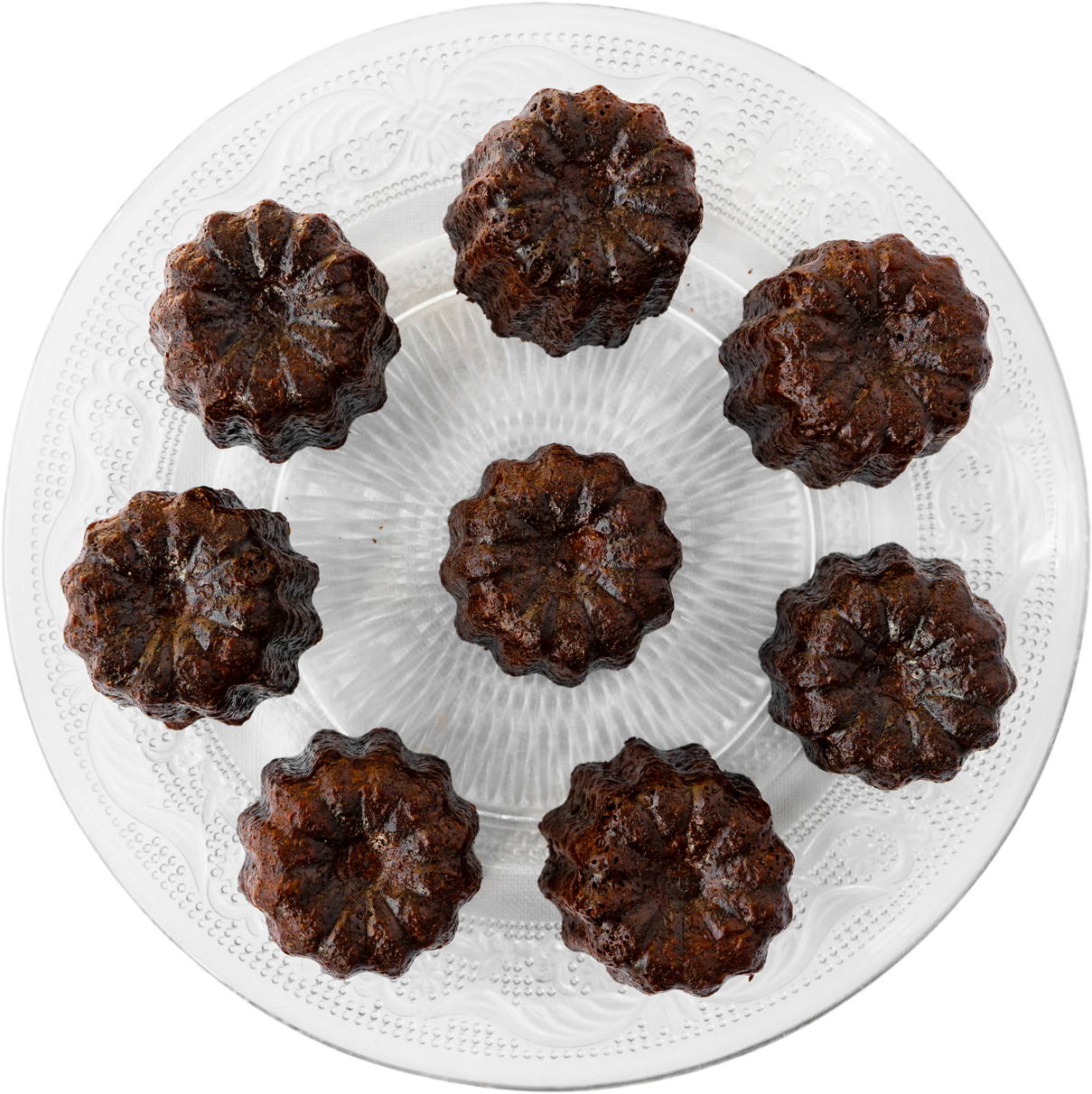 Acht canelés op een geperst glazen schaal, van bovenaf.