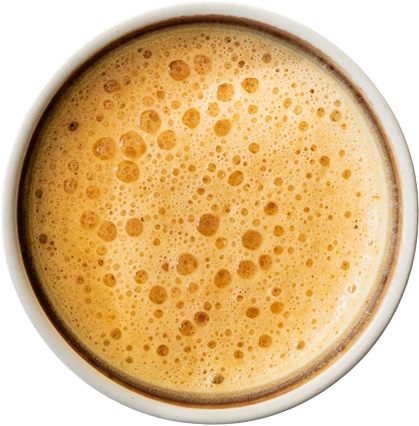 Bovenaanzicht van een witte kom met oranjebruine, schuimende bisque tot aan de rand.