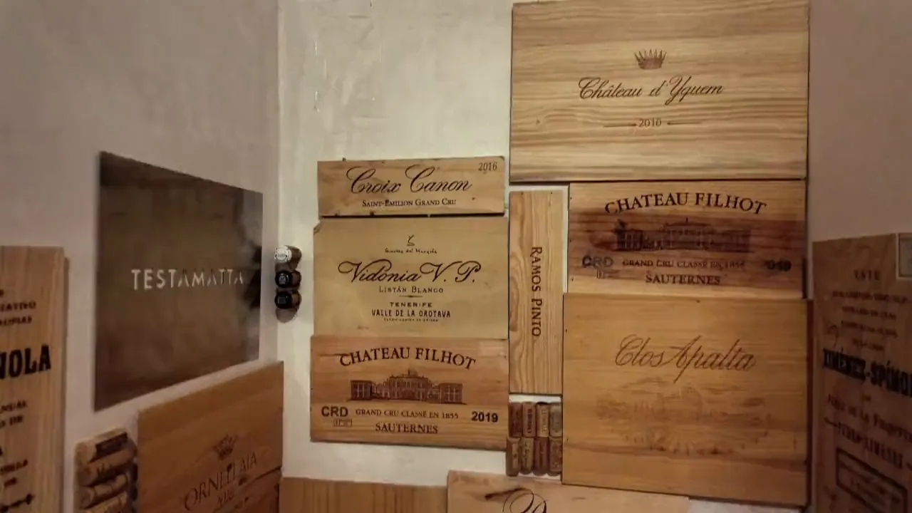 De wijnkelder van Bisque: de wand met wijnkisten van Château d’Yquem, Château Filhot, Clos Apalta en Ornellaia