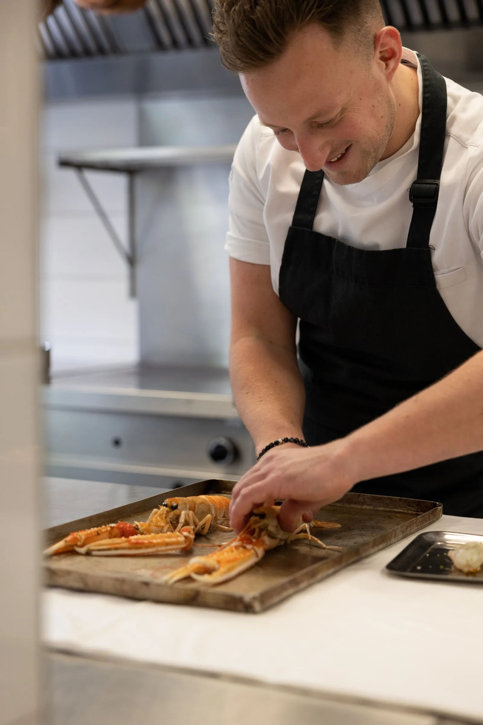 Kok legt langoustines op een bakplaat op het keukenwerkblad.