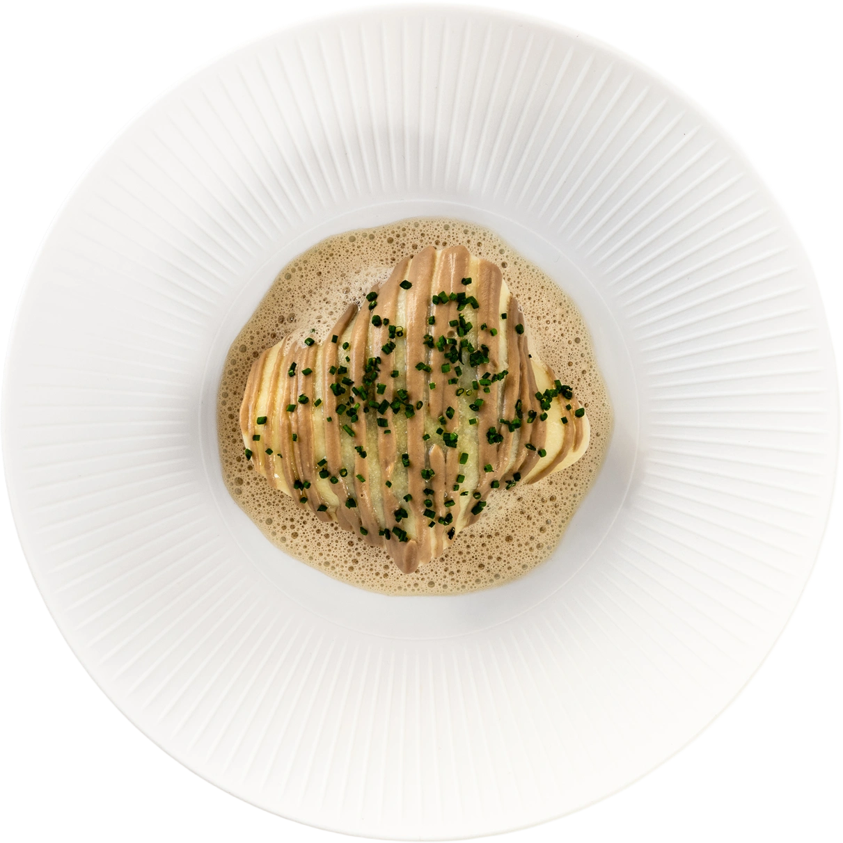 Ravioli in schuimende bruine saus met bieslook, in een geribbeld wit diep bord.